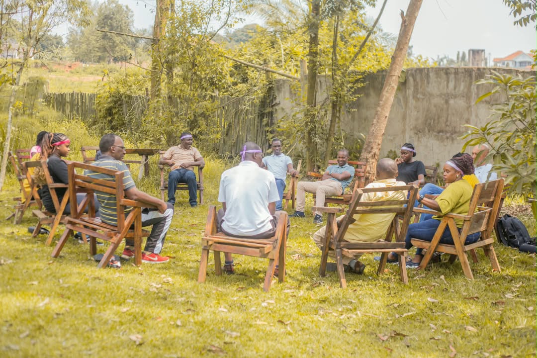 Community members seated in an outdoor dialogue circle under trees